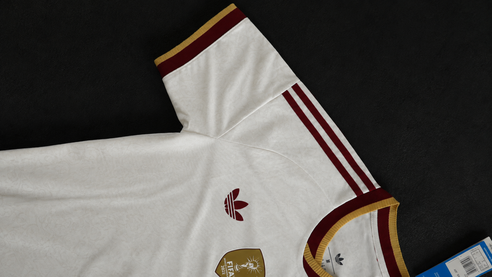 Detalle del hombro y las bandas burdeos de la camiseta blanca