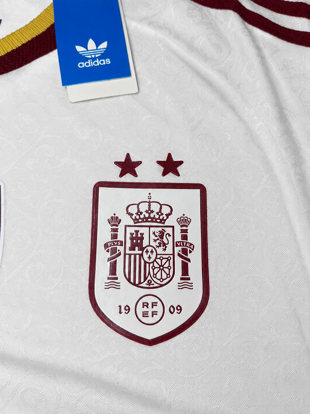 Escudo burdeos con las dos estrellas de la camiseta blanca
